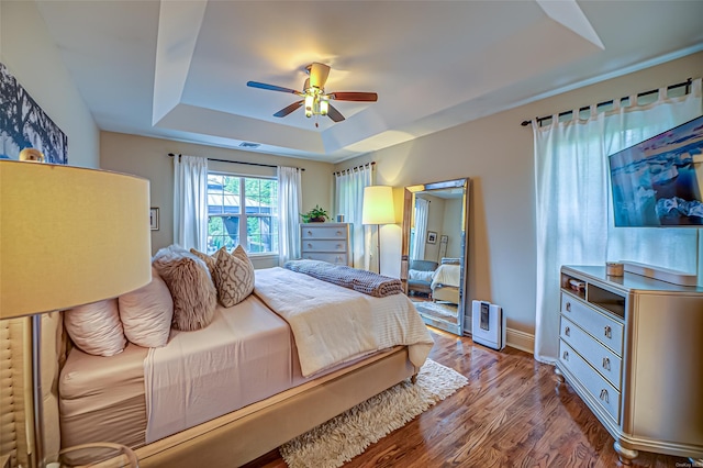 bedroom with a raised ceiling, light hardwood / wood-style flooring, and ceiling fan