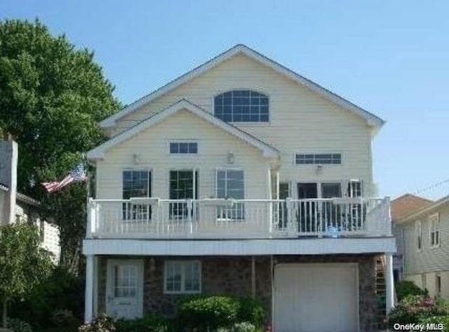 rear view of property with a garage and a balcony