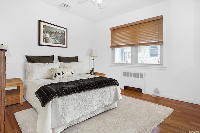 bedroom with radiator heating unit, ceiling fan, and wood-type flooring