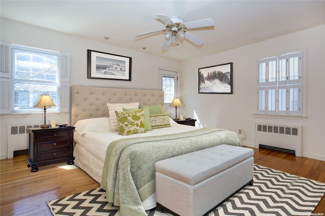 bedroom with radiator heating unit, ceiling fan, and hardwood / wood-style floors