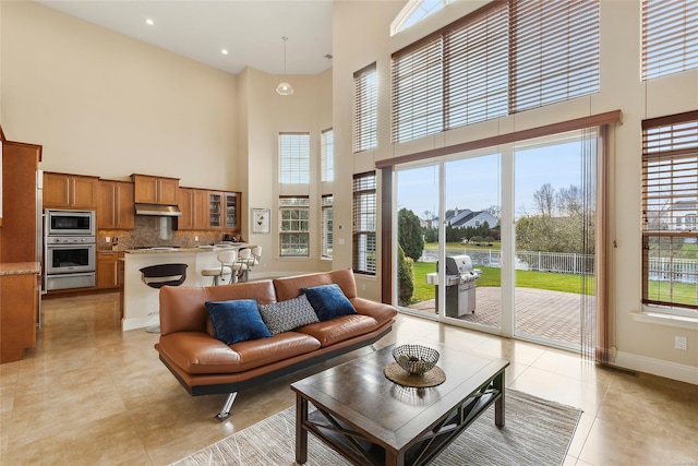 tiled living room featuring a towering ceiling and a healthy amount of sunlight