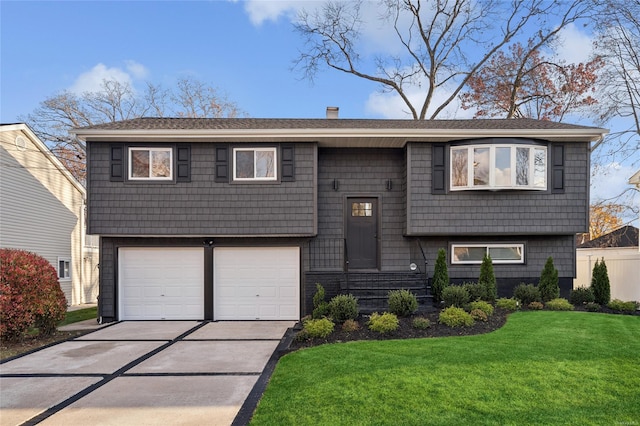 bi-level home featuring a garage, driveway, a chimney, and a front lawn