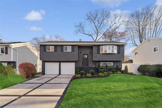 raised ranch with a front lawn, an attached garage, fence, and driveway