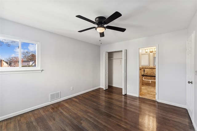 unfurnished bedroom featuring dark hardwood / wood-style flooring, connected bathroom, a closet, and ceiling fan