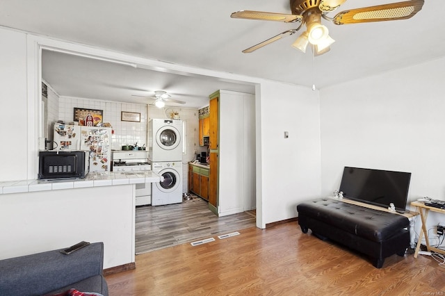 interior space with light wood-type flooring, ceiling fan, and stacked washing maching and dryer