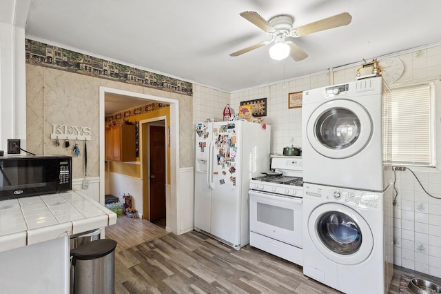 clothes washing area with wood-type flooring, stacked washer / drying machine, and ceiling fan