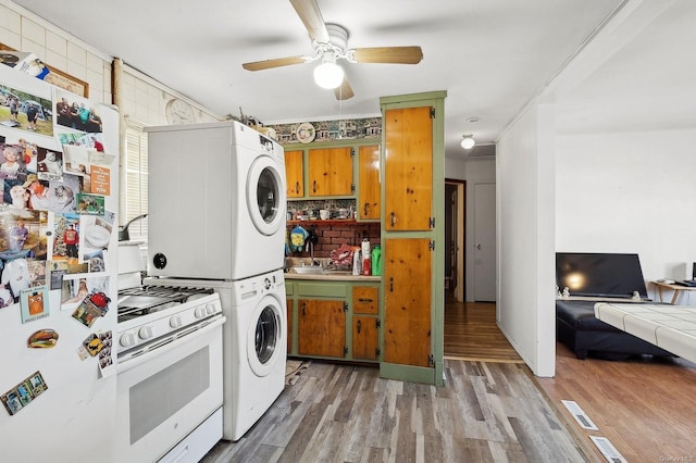 kitchen featuring tasteful backsplash, stacked washer and dryer, fridge, light hardwood / wood-style floors, and white gas range oven