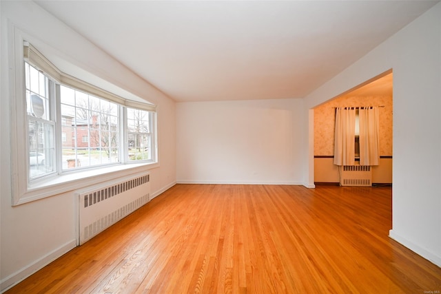 empty room featuring radiator heating unit and hardwood / wood-style floors