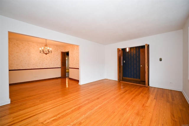 spare room featuring a notable chandelier and hardwood / wood-style flooring