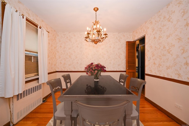 dining room featuring hardwood / wood-style floors, radiator heating unit, and a chandelier