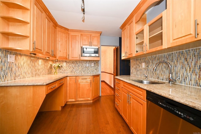 kitchen with light stone countertops, sink, stainless steel appliances, and hardwood / wood-style flooring