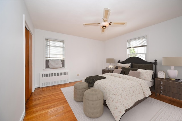 bedroom featuring ceiling fan, radiator heating unit, and light hardwood / wood-style flooring