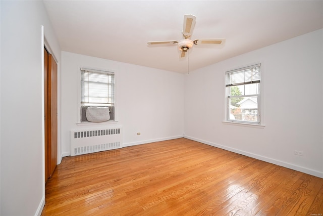 spare room with ceiling fan, light hardwood / wood-style floors, and radiator