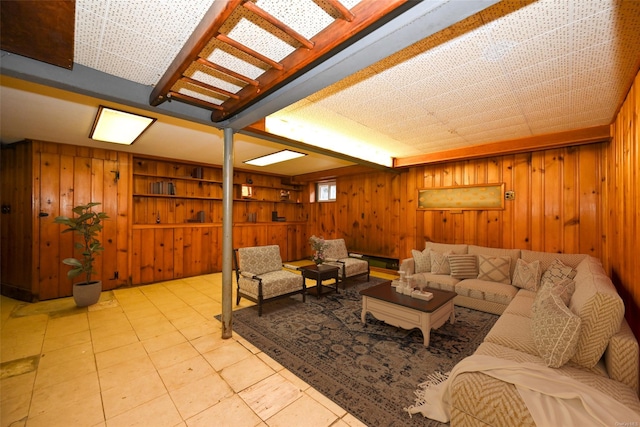 living room with built in shelves, wood walls, and light tile patterned floors