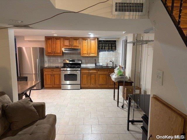 kitchen with appliances with stainless steel finishes, sink, backsplash, and range hood