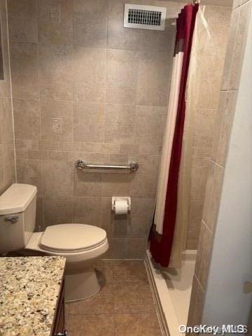 bathroom with a shower with shower curtain, vanity, toilet, and tile patterned flooring