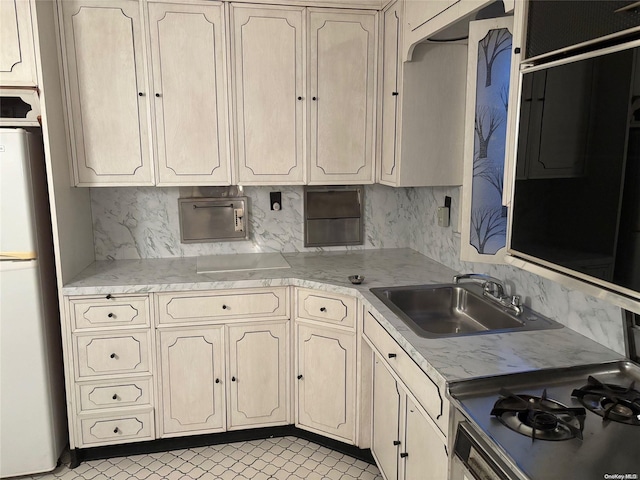 kitchen featuring tasteful backsplash, fridge, and sink