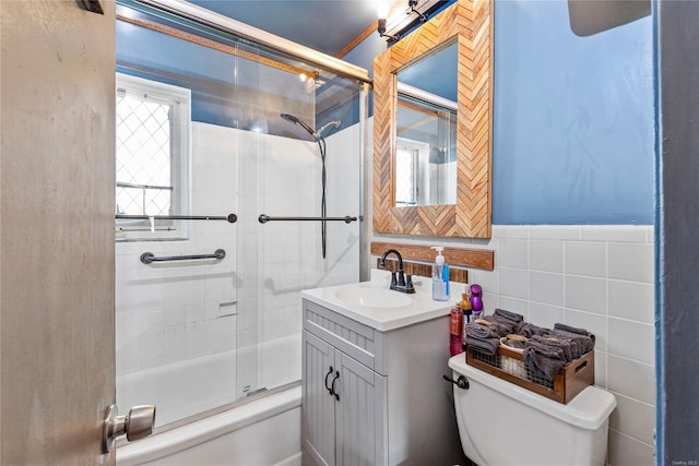 full bathroom with vanity, combined bath / shower with glass door, tile walls, and toilet