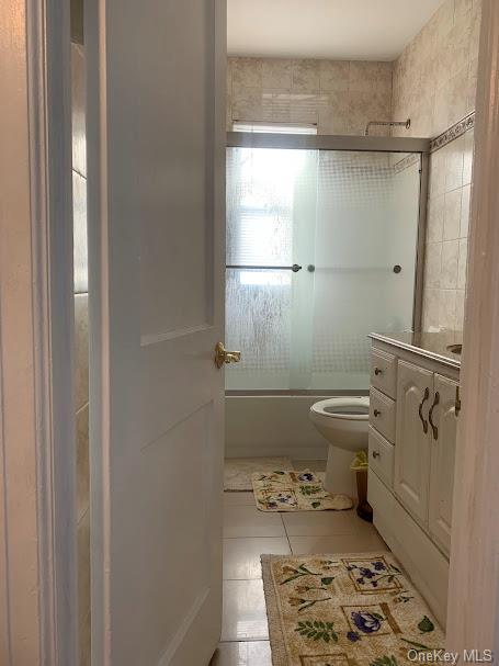 full bathroom featuring tile patterned floors, vanity, toilet, and enclosed tub / shower combo