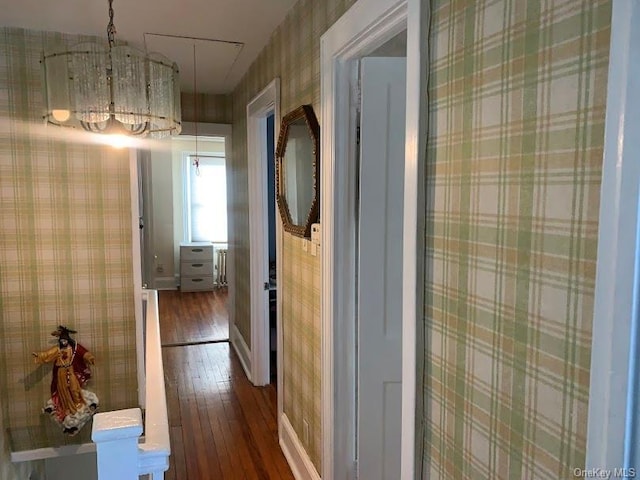 hall with hardwood / wood-style flooring and a notable chandelier