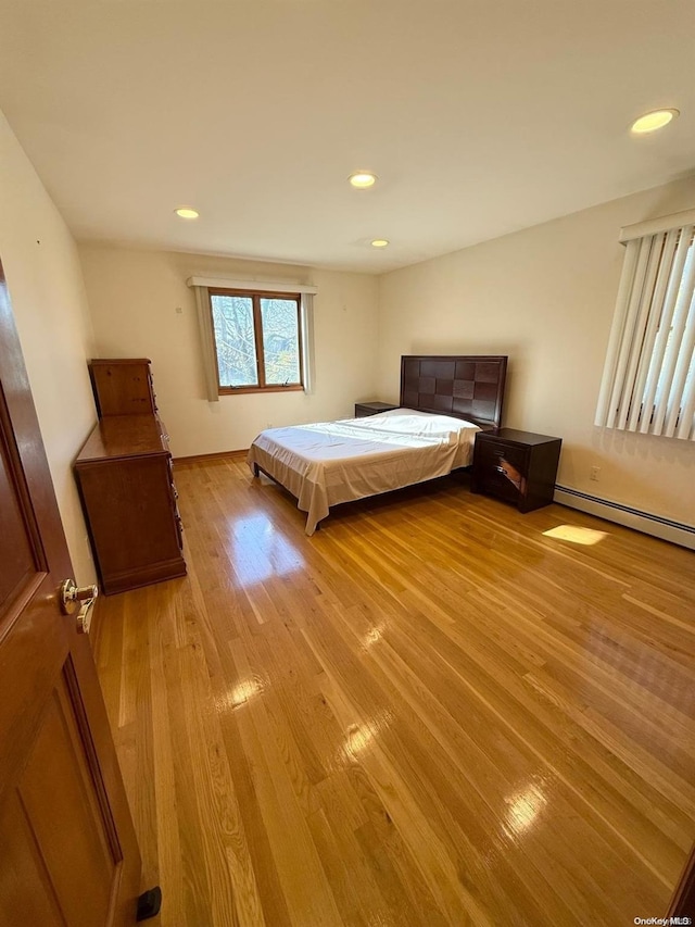 unfurnished bedroom with baseboard heating and light hardwood / wood-style floors