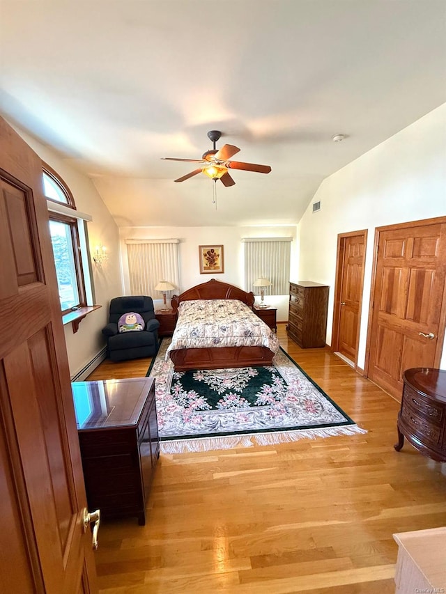 bedroom with lofted ceiling, a baseboard heating unit, ceiling fan, and light hardwood / wood-style floors