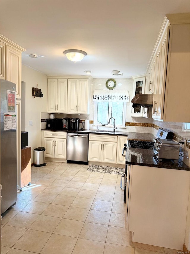 kitchen featuring stainless steel appliances, dark stone countertops, sink, and light tile patterned floors