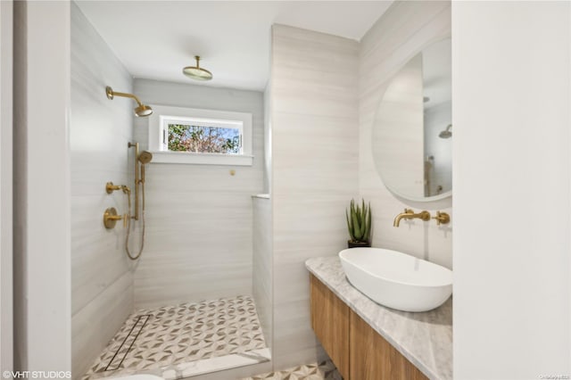 bathroom with tile patterned floors, tiled shower, and sink