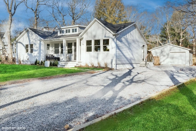 view of front facade featuring covered porch, a garage, a front lawn, and an outdoor structure