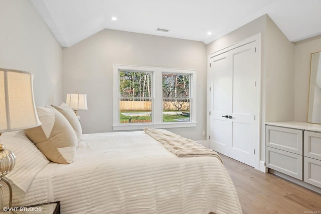 bedroom featuring light hardwood / wood-style floors, a closet, and lofted ceiling