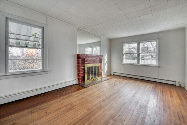 unfurnished living room with hardwood / wood-style floors, a brick fireplace, and baseboard heating