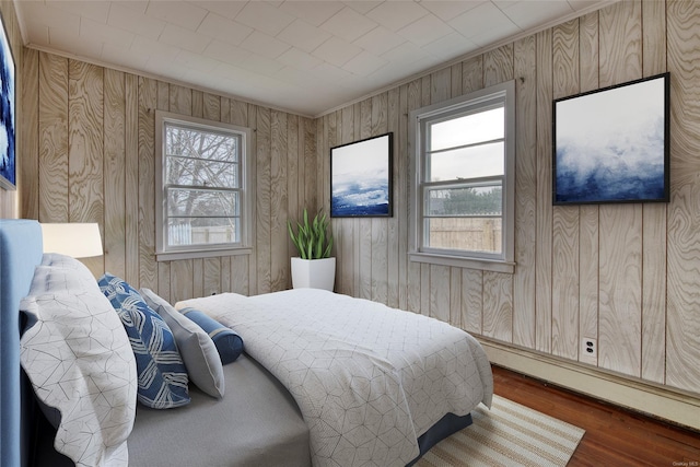 bedroom with crown molding, dark hardwood / wood-style flooring, baseboard heating, and multiple windows