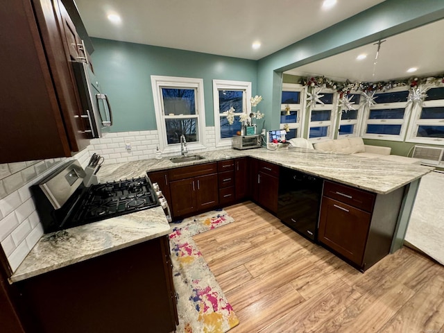 kitchen with kitchen peninsula, light stone counters, and black appliances