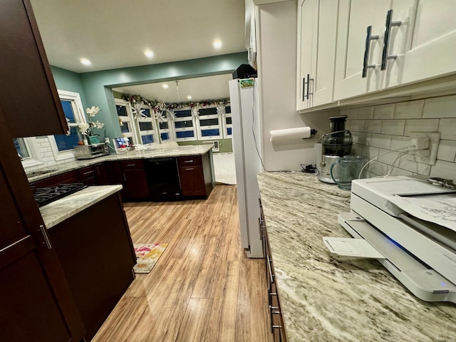 kitchen featuring pendant lighting, black appliances, light hardwood / wood-style flooring, light stone counters, and white cabinetry