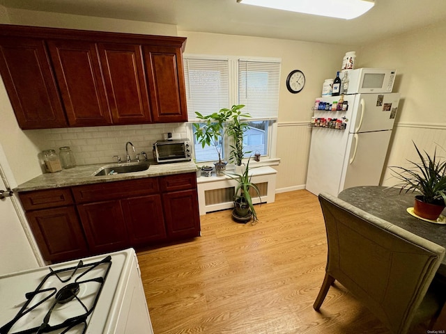 kitchen with decorative backsplash, sink, white appliances, and light wood-type flooring