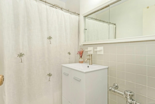 bathroom with walk in shower, vanity, and tile walls