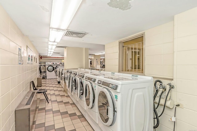 washroom with tile walls and washing machine and clothes dryer