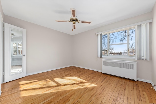 empty room with ceiling fan, radiator, and light wood-type flooring