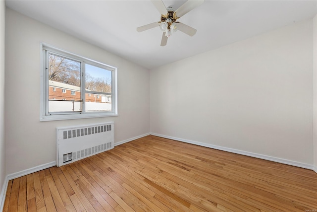 empty room featuring ceiling fan, radiator, and light wood-type flooring