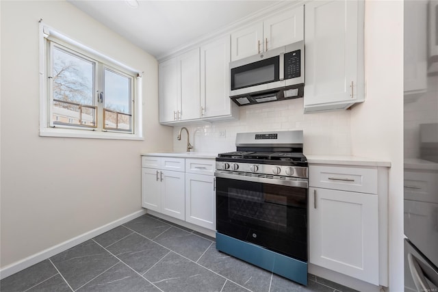 kitchen featuring dark tile patterned floors, white cabinetry, appliances with stainless steel finishes, and sink