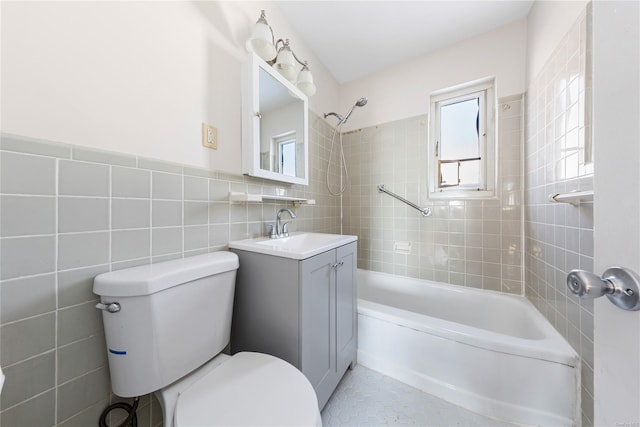 full bathroom with tile walls, vanity, tiled shower / bath combo, and toilet