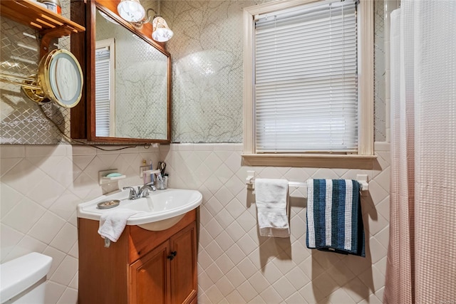 bathroom with vanity, toilet, and tile walls