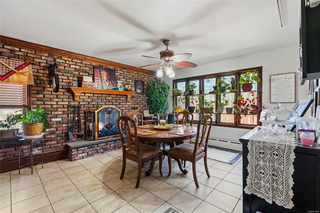 dining space with ceiling fan, a brick fireplace, brick wall, a baseboard heating unit, and light tile patterned floors