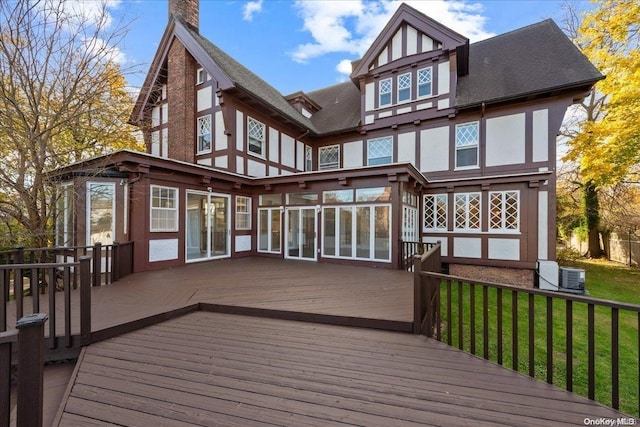 wooden terrace featuring central air condition unit, a lawn, and a sunroom