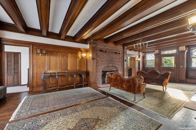 living room with wood walls, dark hardwood / wood-style floors, a fireplace, beam ceiling, and a chandelier