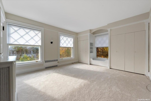 unfurnished bedroom featuring light colored carpet and radiator