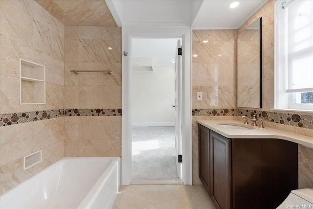 bathroom with a bath, vanity, and tile walls