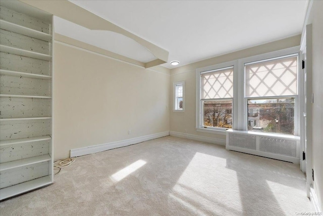 unfurnished room with light colored carpet and radiator heating unit