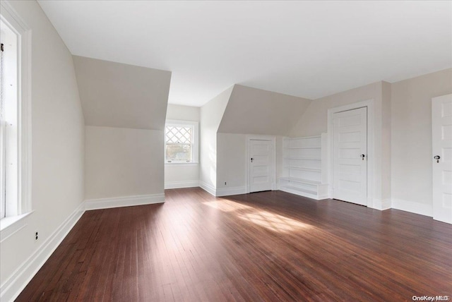 bonus room with built in shelves and dark wood-type flooring