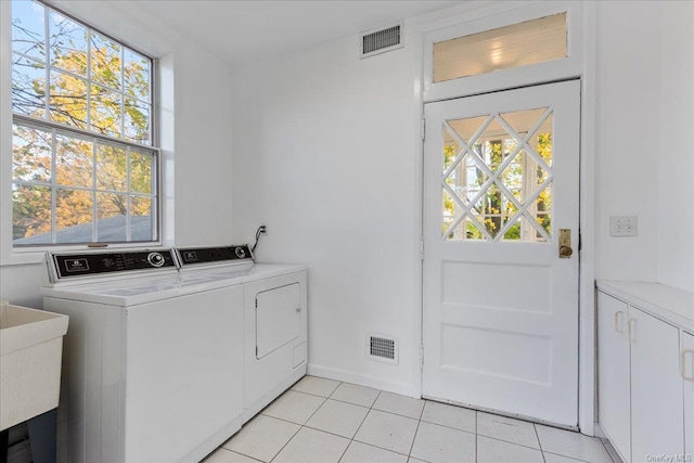 clothes washing area with a wealth of natural light, washer and clothes dryer, and light tile patterned floors